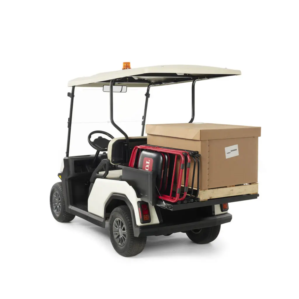 Cargo Bed Attachment for Toro Vista Passenger Transport Vehicle, showing a black box protuding out the back of a golf cart esque vehicle with a box and chairs on top