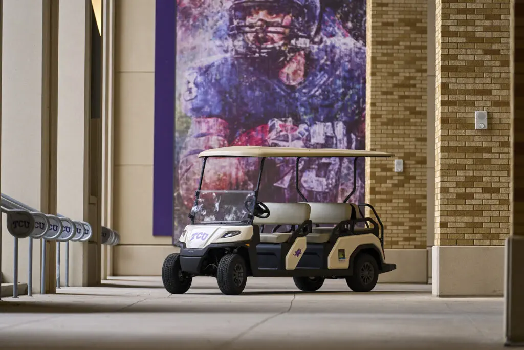 The Toro Vista Passenger Transport Vehicle parked in front of a image of an american football player at Texas Christian University