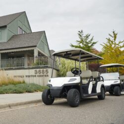 Toro Vista 4-seater golf cart with beige seats and a white roof, parked outside the Oswald Visitor Center, with another golf cart in the background