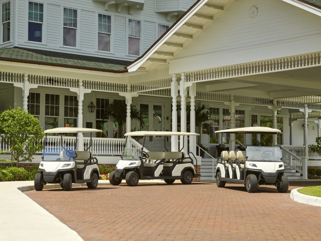 Three Toro Vista Passenger Transport Vehicles parked infront of a vintage style club house