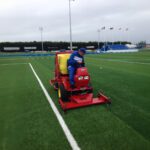 SMG SportChamp SC2D ride-on artificial turf cleaner in use on a football field in Christchurch