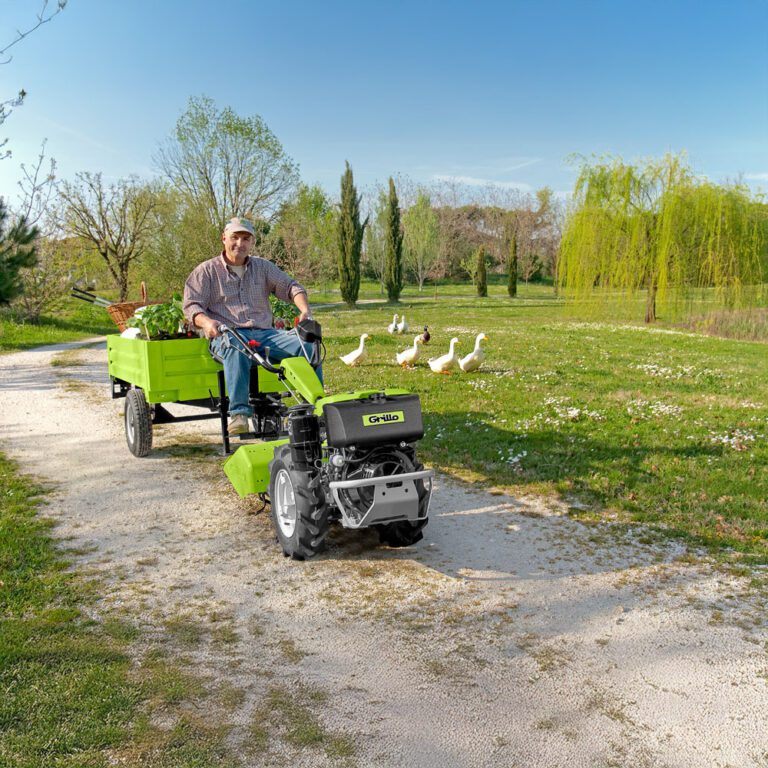 Man riding Grillo G107d walk behind tractor with trunk attachment 