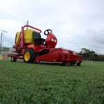 SMG SportChamp SC2D ride-on cleaner, designed for maintaining synthetic turf, seen on a soccer field.