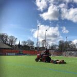 Tractor towing SMG TurfCare TCA1400 turf cleaner on a synthetic soccer field for field maintenance.