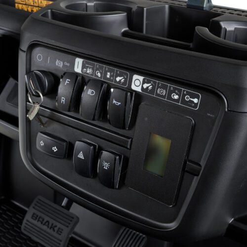 Close-up of the control panel in a Toro utility vehicle, showing key ignition, gear switches, light controls, and indicators