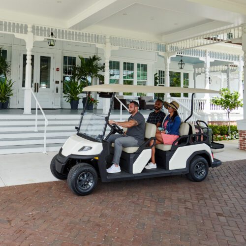 Toro Vista 6-seater utility vehicle with beige seats and a white roof, parked outside a hotel entrance, designed for transporting guests and equipment