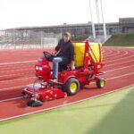 SMG SportChamp SC2D ride-on machine cleaning an athletic track at a sports facility.