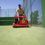 SMG TurfSoft TS2 artificial turf cleaner being pushed across a green turf field, cleaning the surface efficiently.