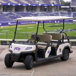 Toro Vista 6-seater golf cart customized with TCU logos, beige seating, and a white roof, parked at a stadium with a football field and purple stands in the background