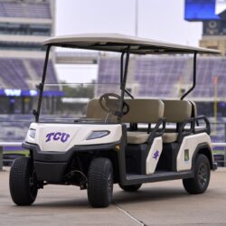 Front view of the Toro Vista 6-seater golf cart, with TCU branding and beige seats, parked near a stadium with purple bleachers visible in the background