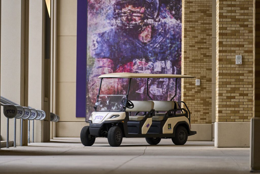 The Toro Vista Passenger Transport Vehicle parked in front of a image of an american football player at Texas Christian University